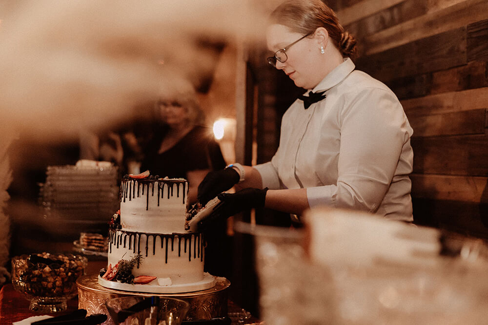 A staff member cutting a wedding cake.