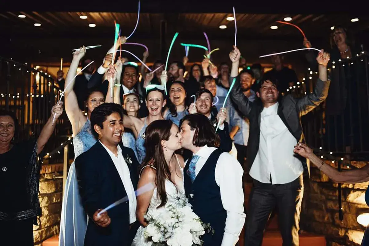 lets-plan-your-big-day A bride and groom kissing while the wedding party cheers