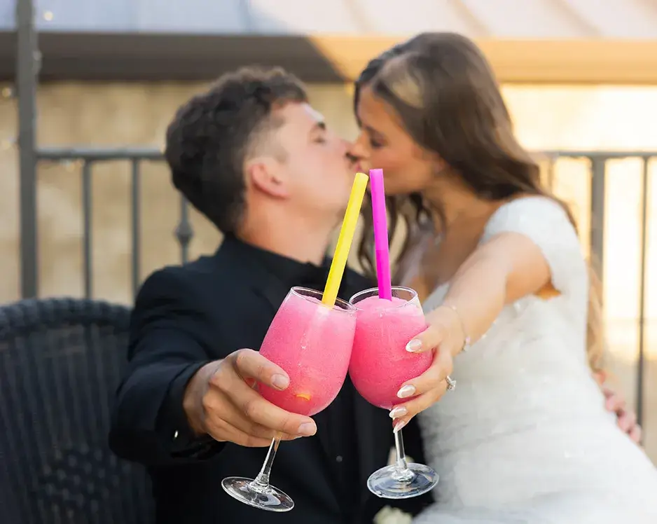 wine-slushies A bride and groom clinking wine slushies together at affordable wedding venues in Edmond