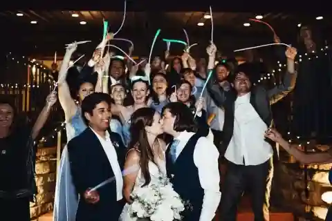 A bride and groom kissing while the wedding party cheers