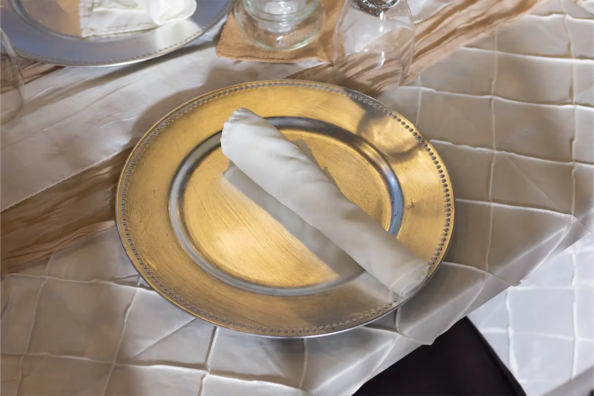 A silver plate with a white linen-rolled napkin resting on it