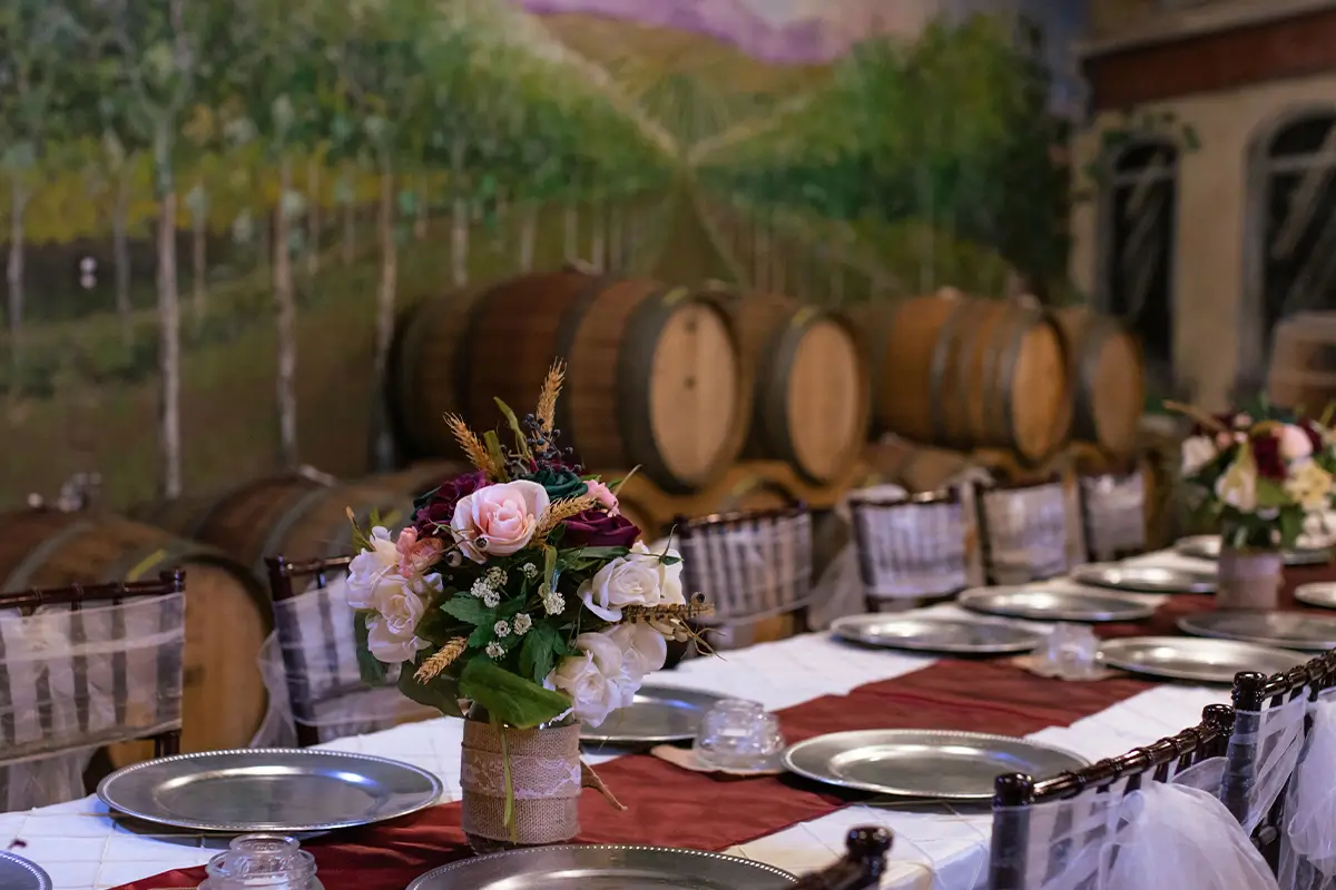 Elegant fall wedding reception table with floral centerpiece in a vineyard-inspired venue.
